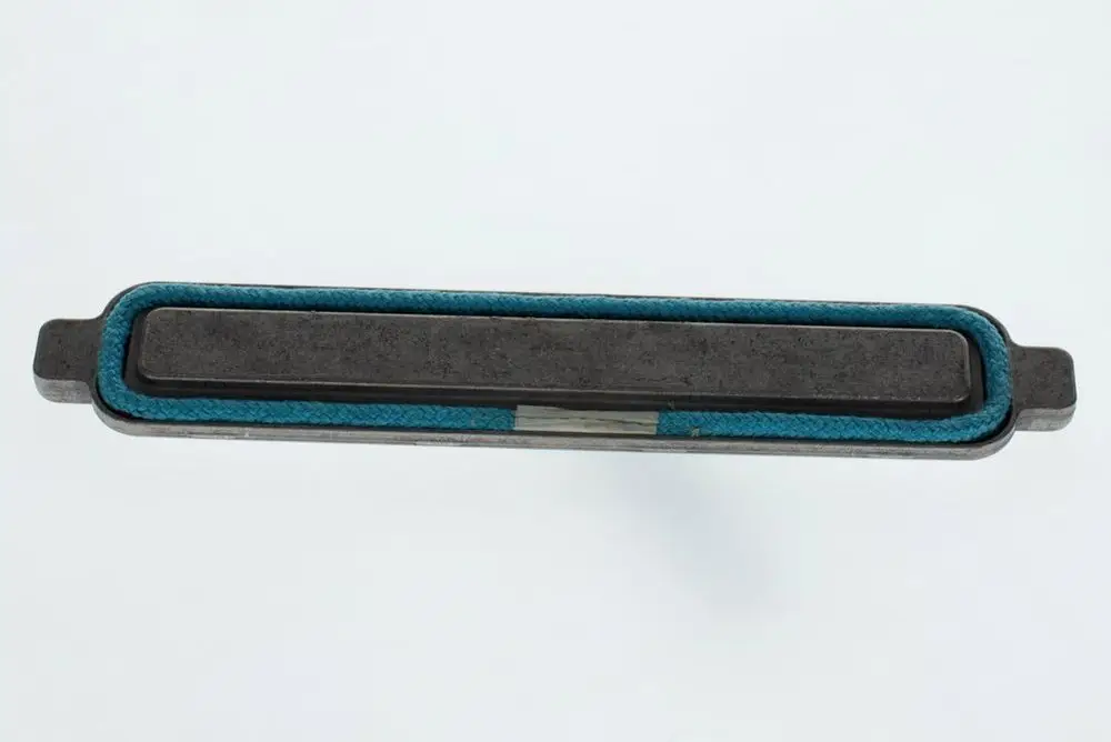 Bosch-Produkt mit länglichem, flachen Metallkörper, umgeben von einem blauen Gummiring, auf hellem Hintergrund.